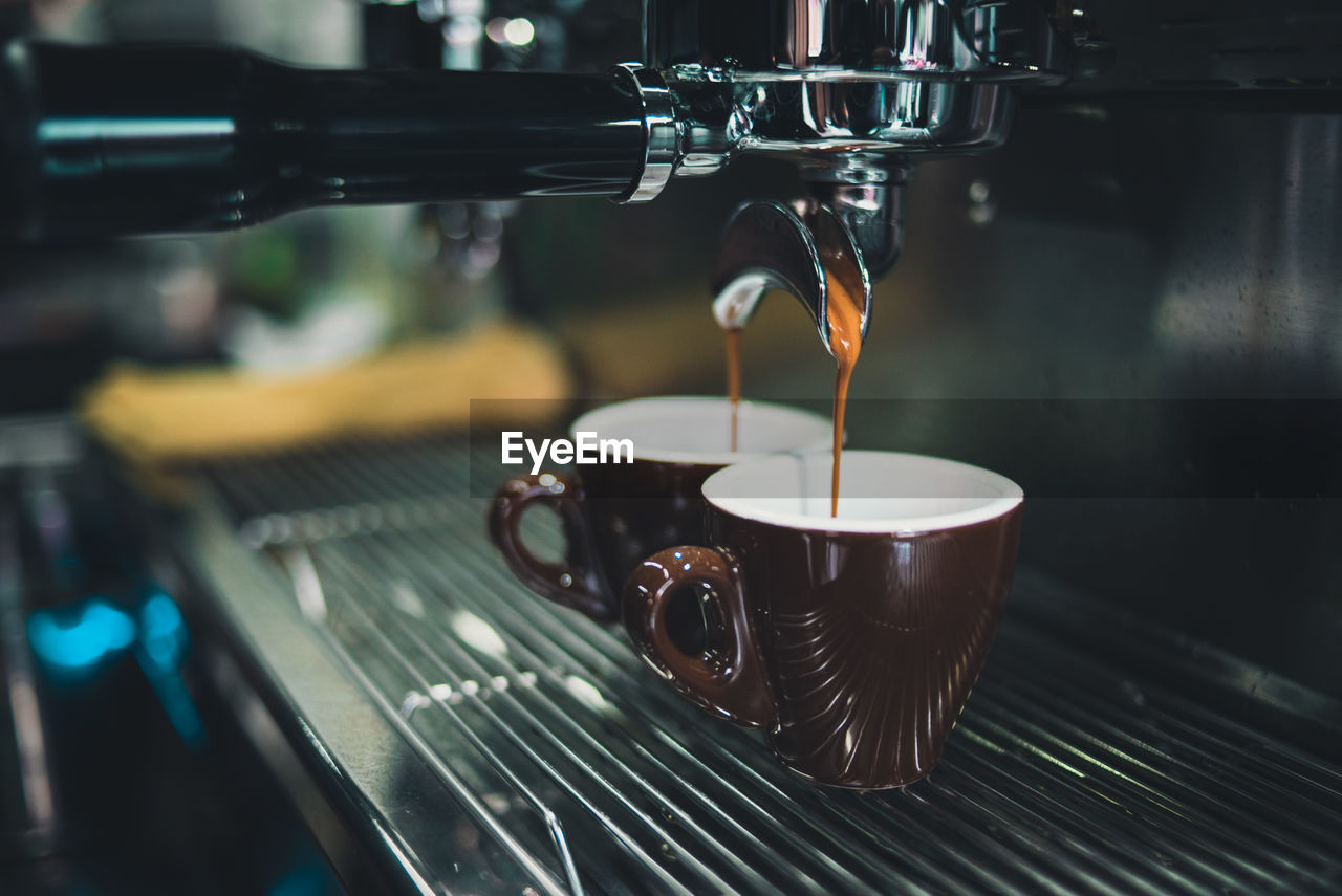 Close-up of coffee cup on espresso maker in cafe