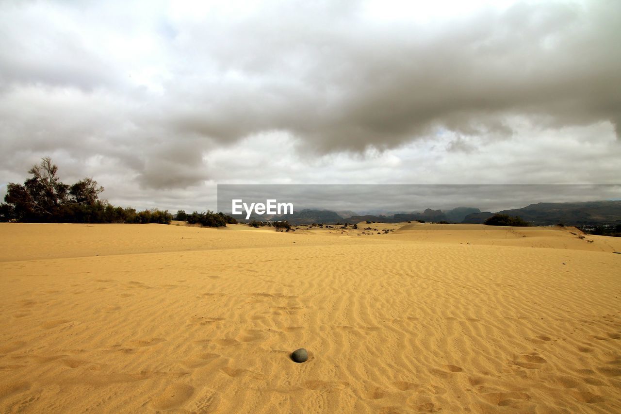 Scenic view of desert against cloudy sky