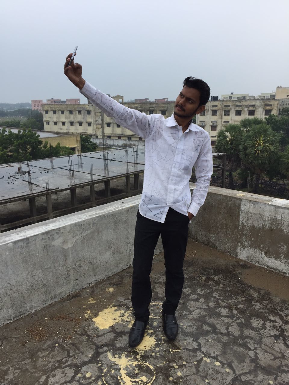 Full length of young man taking selfie through mobile phone while standing on building terrace