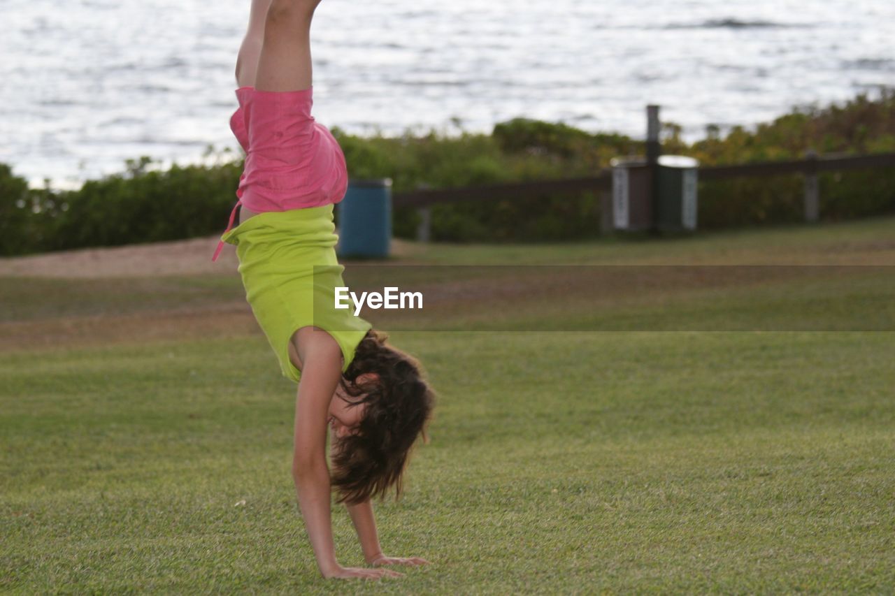 Full length of girl in handstand on grass