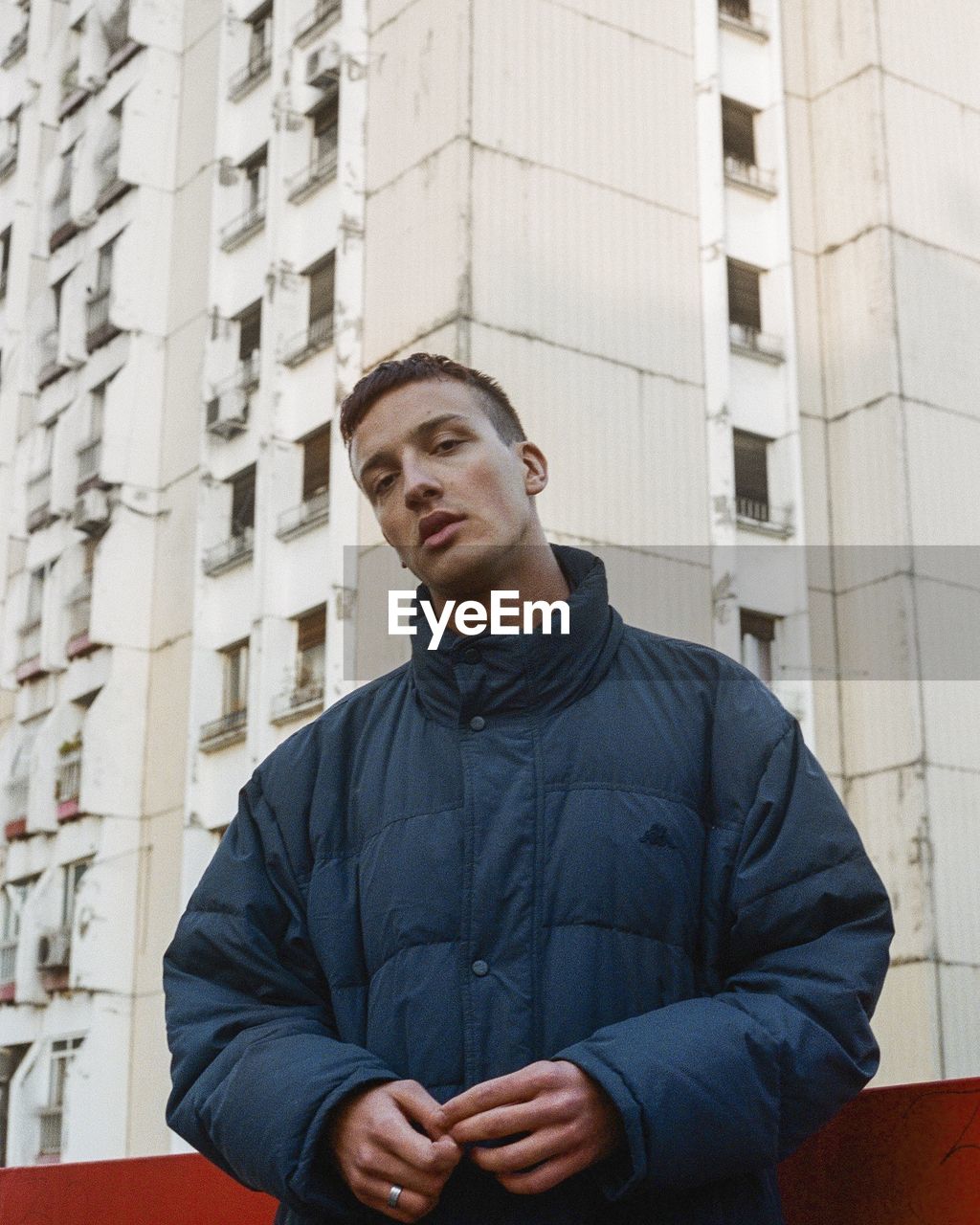 Portrait of young man standing against building