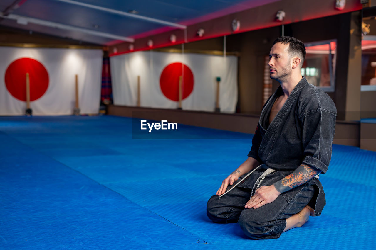 Portrait of karate man in focus position with japan flag on the wall