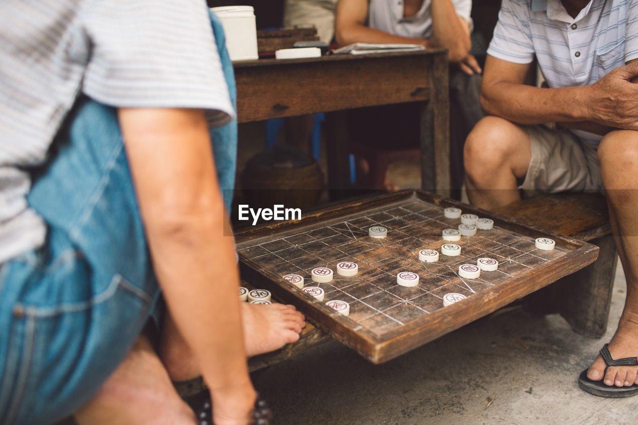 Low section of men playing board game outdoors