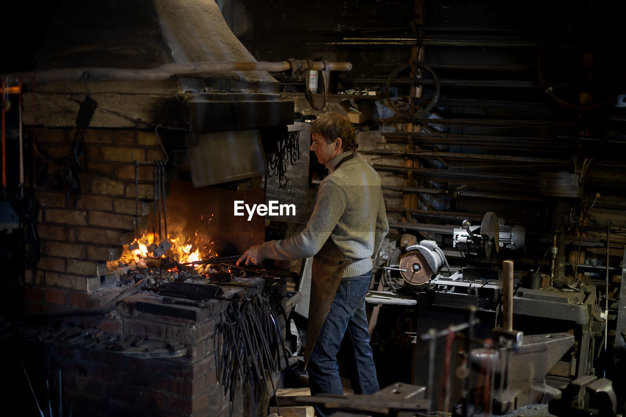 Latvian blacksmith working with open fire in furnace. the blacksmith forging hot iron in workshop