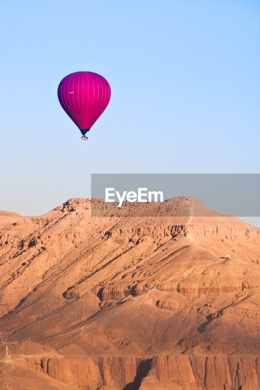 Hot air balloon in desert against clear sky
