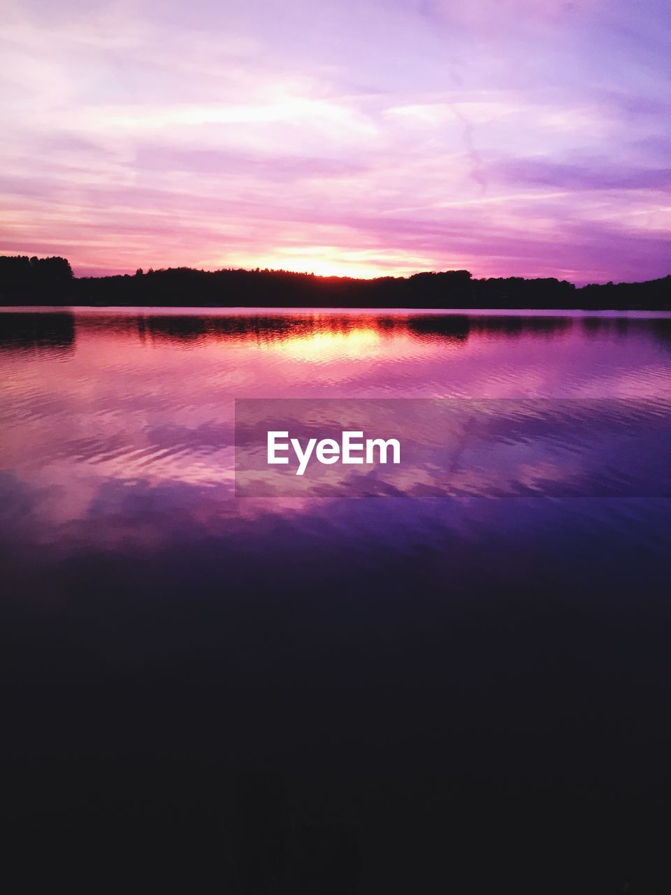 SCENIC VIEW OF CALM LAKE AT SUNSET