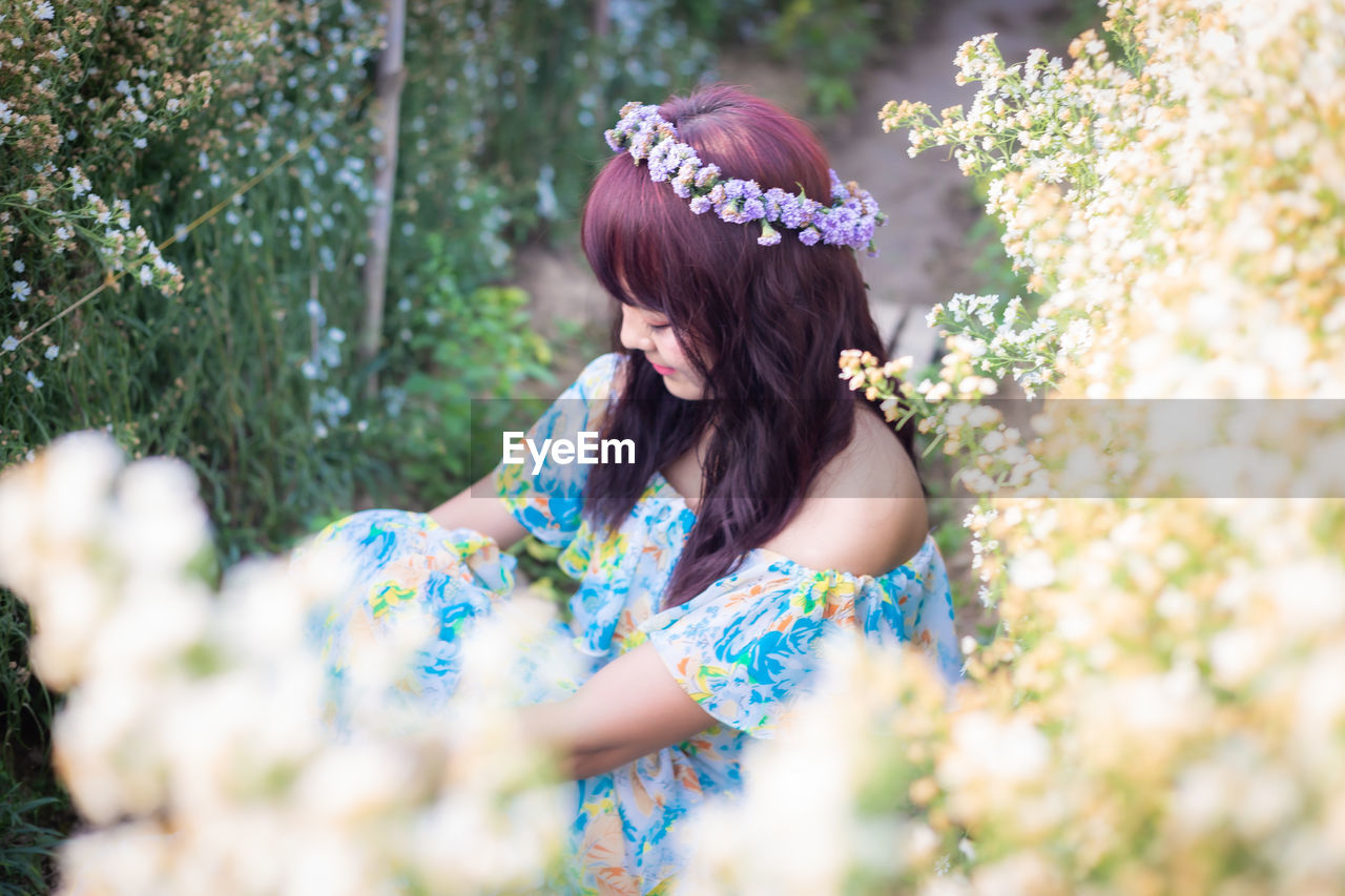 MIDSECTION OF WOMAN WITH FLOWER PETALS ON PLANT