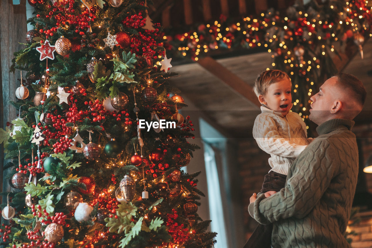 Smile little boy and dad having fun with each other hugs and kisses indoor waiting santa.