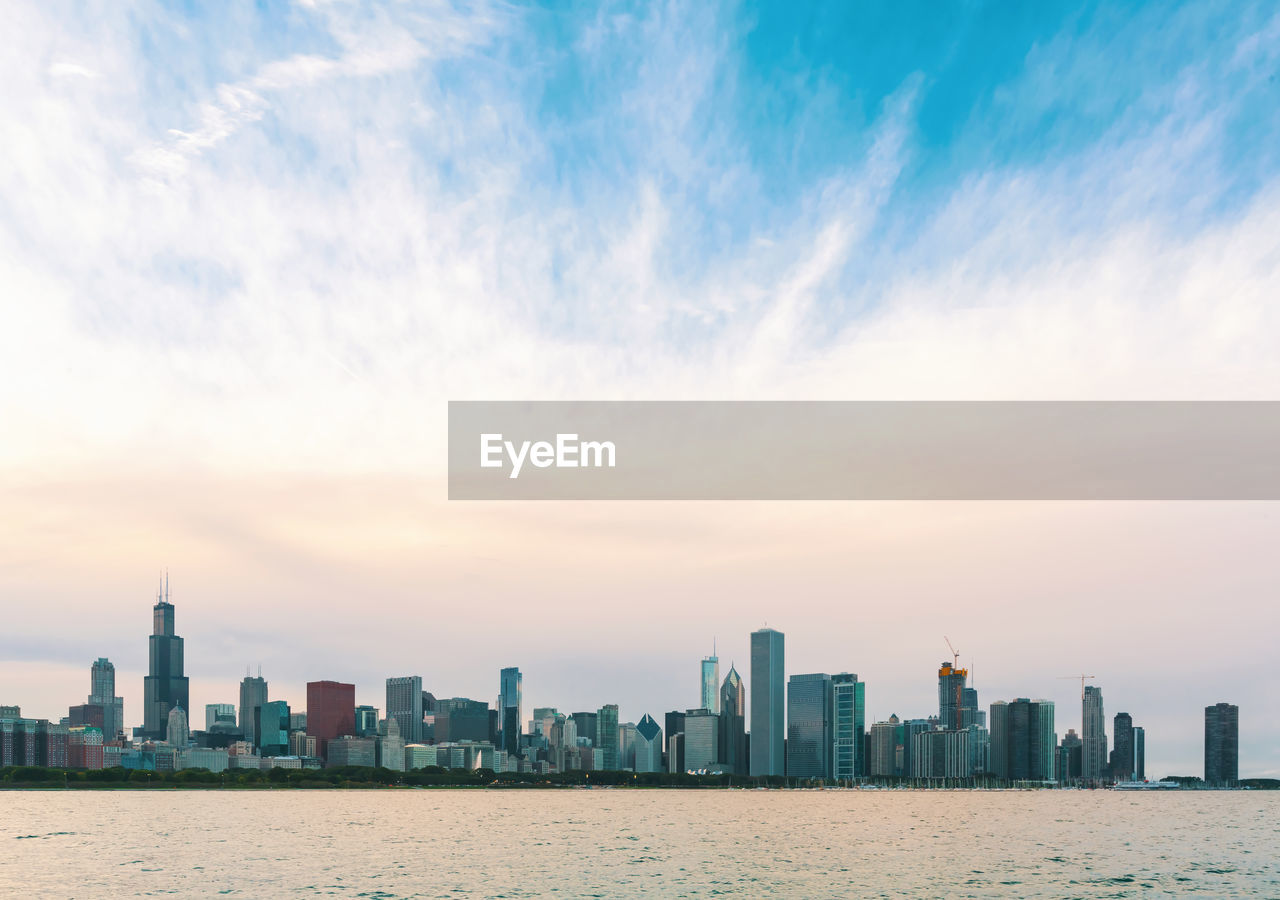 Sea by modern buildings against sky in city