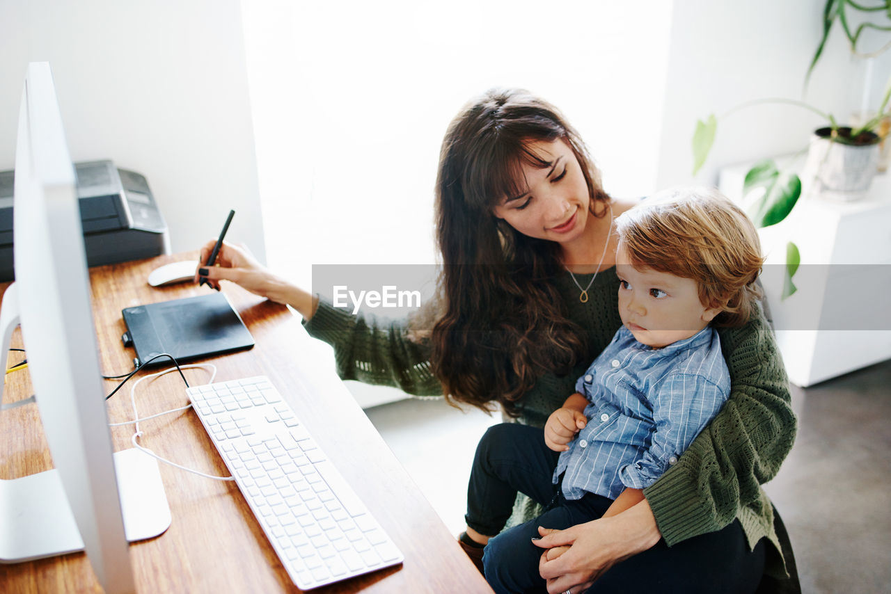 Mother and daughter sitting on table