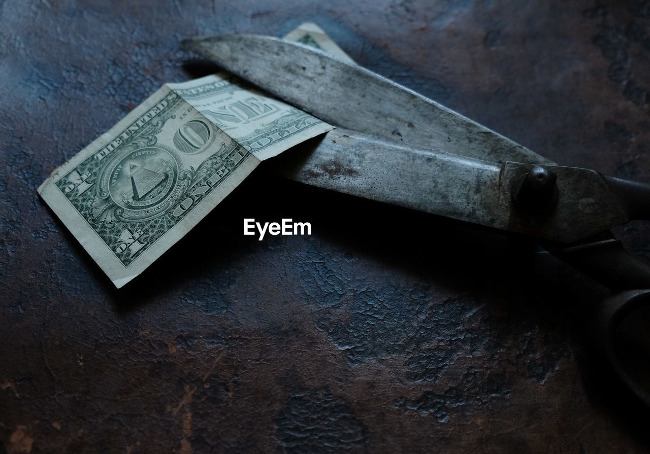 Close-up of scissors and paper currency on table