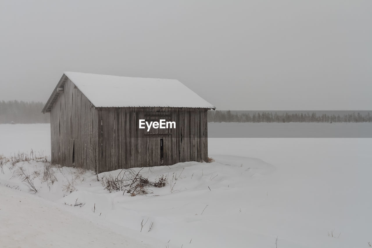 An old abandoned barn house stands on the snowy fields at the rural finland. 