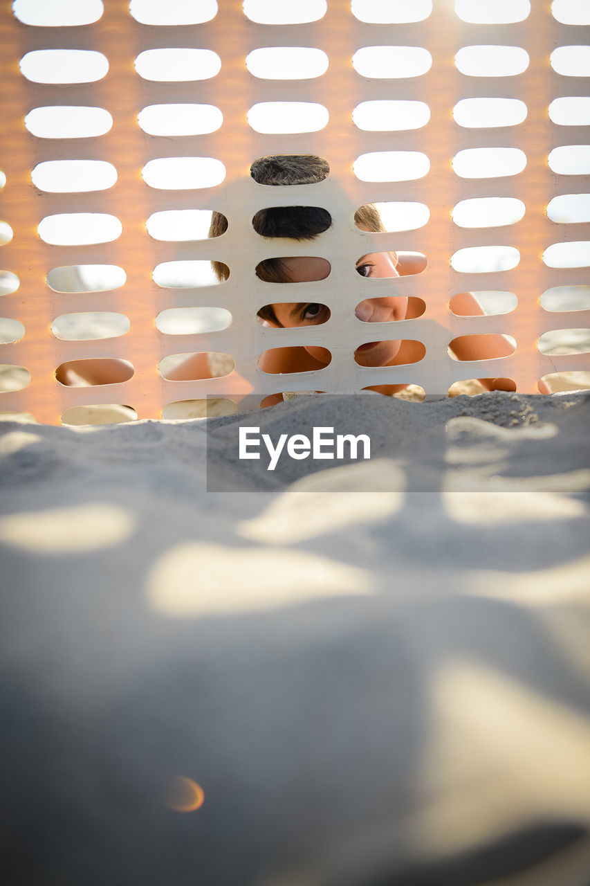 Portrait of boy seen through metal grate at beach