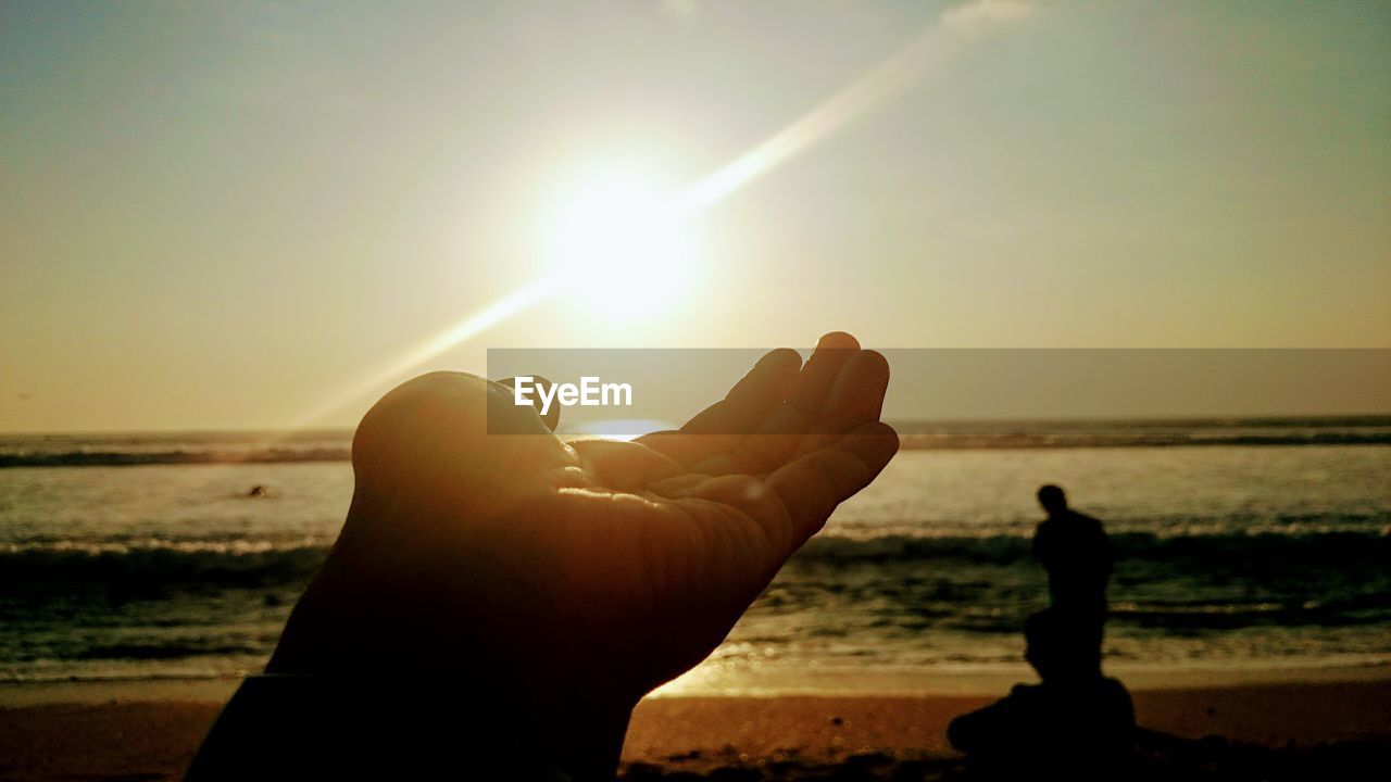 PEOPLE HANDS ON BEACH DURING SUNSET