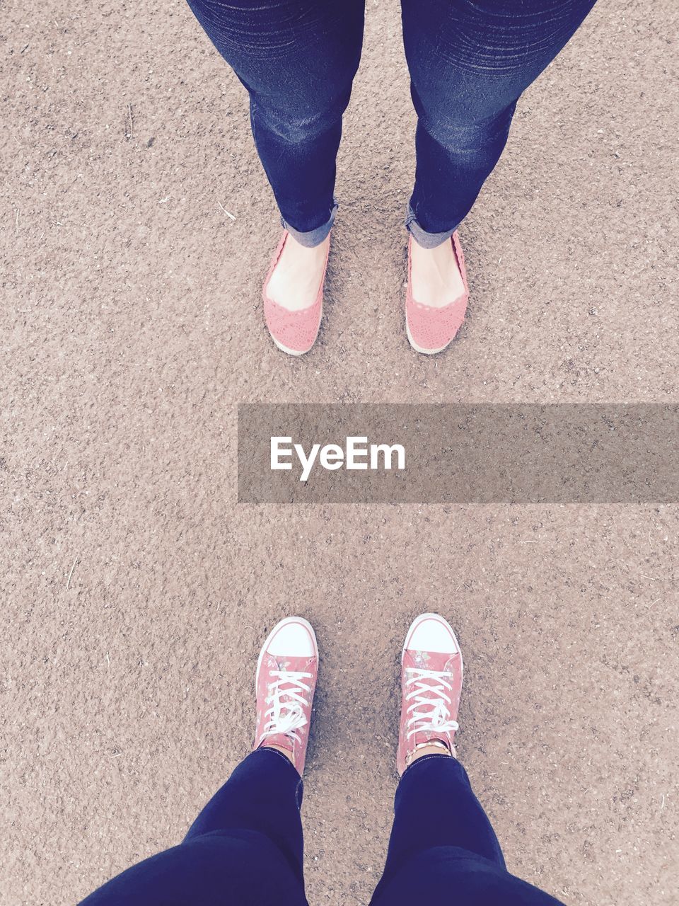 Low section of women standing with pink footwear