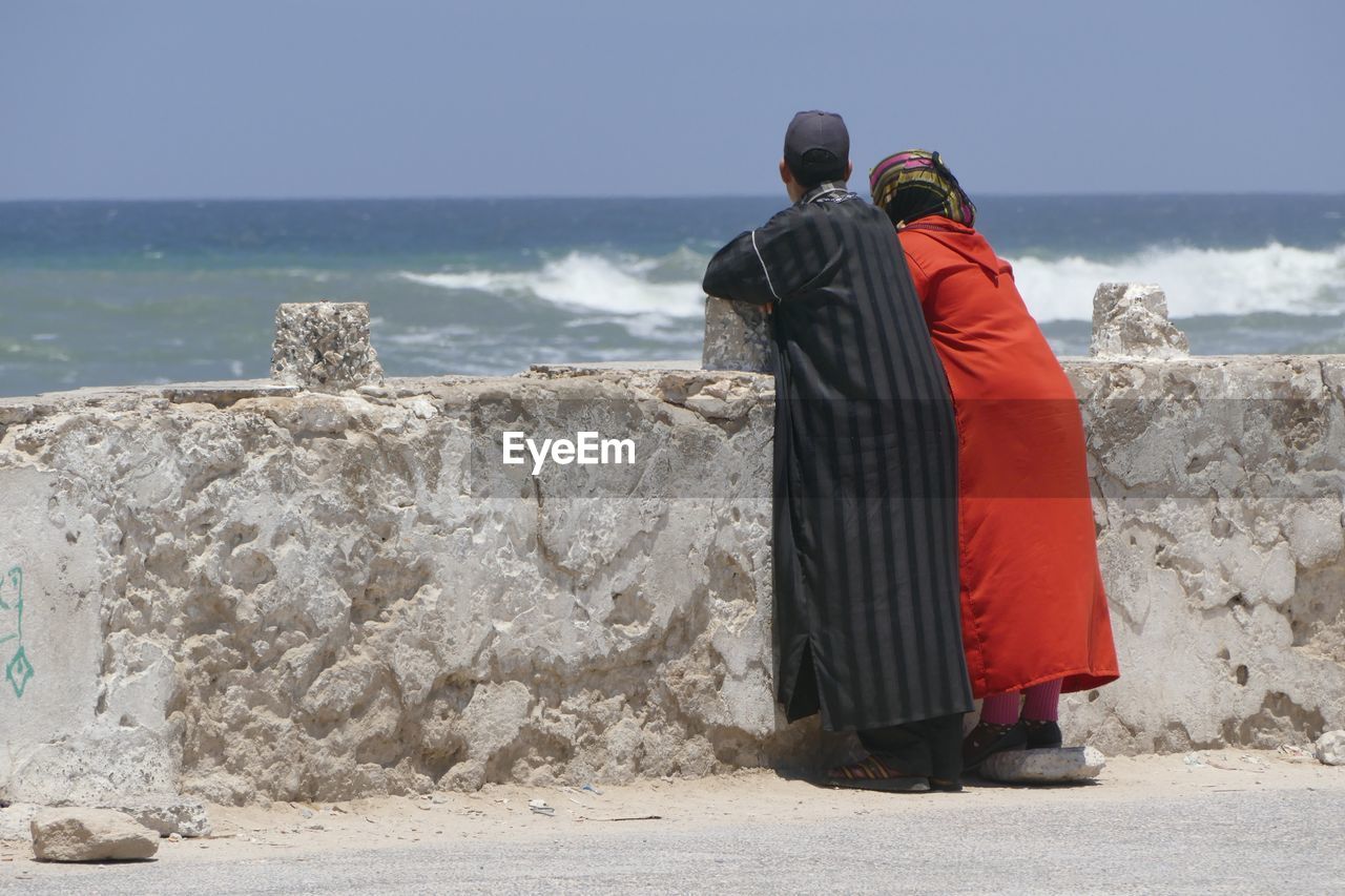 Woman and man in traditional clothing standing on cement jetty