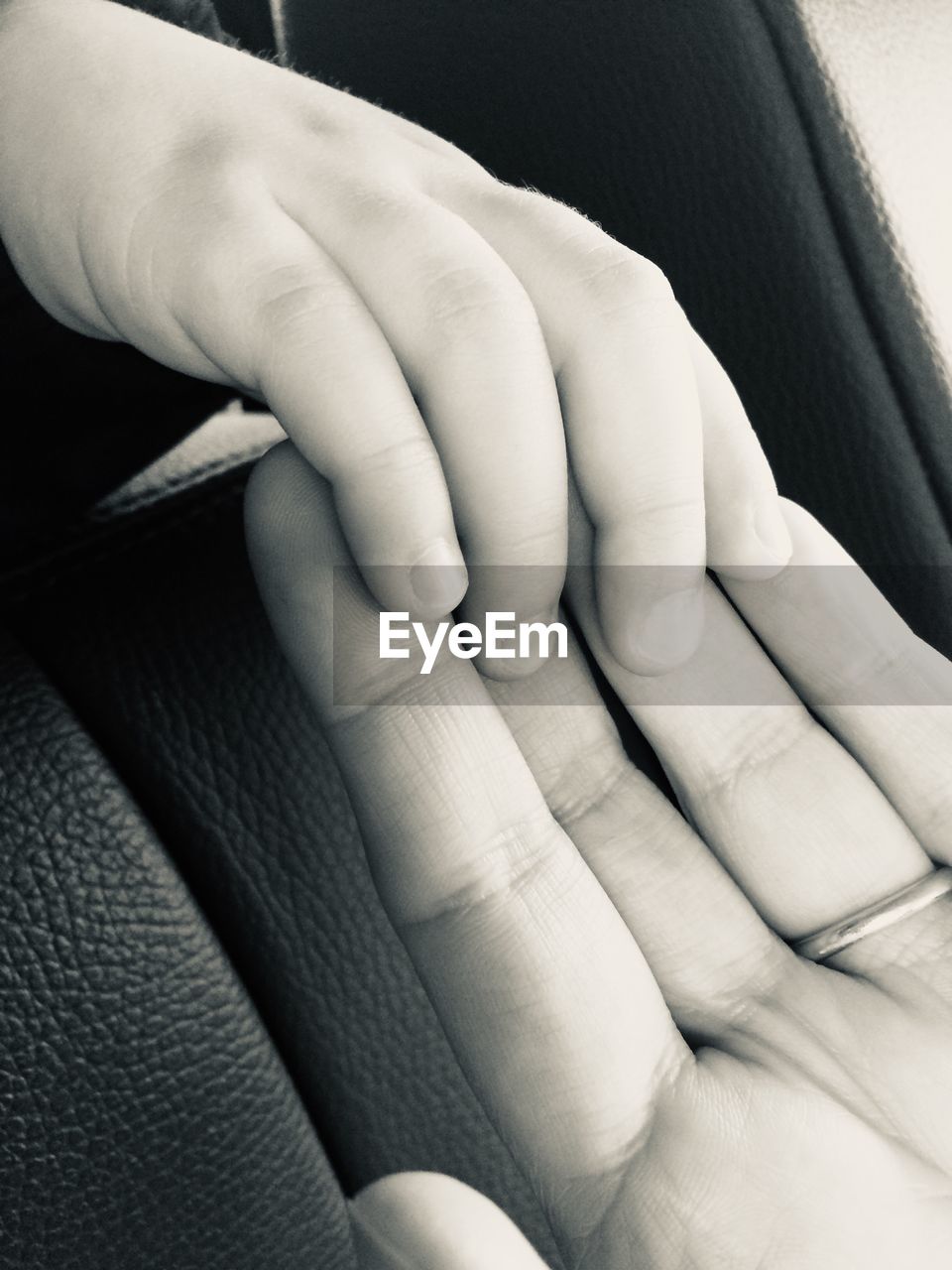 Close-up of baby touching parent hand in car