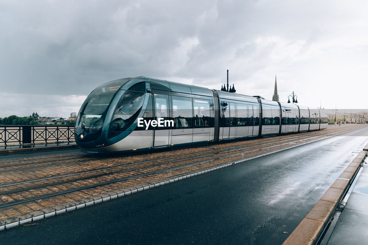 Train on bridge in city against sky