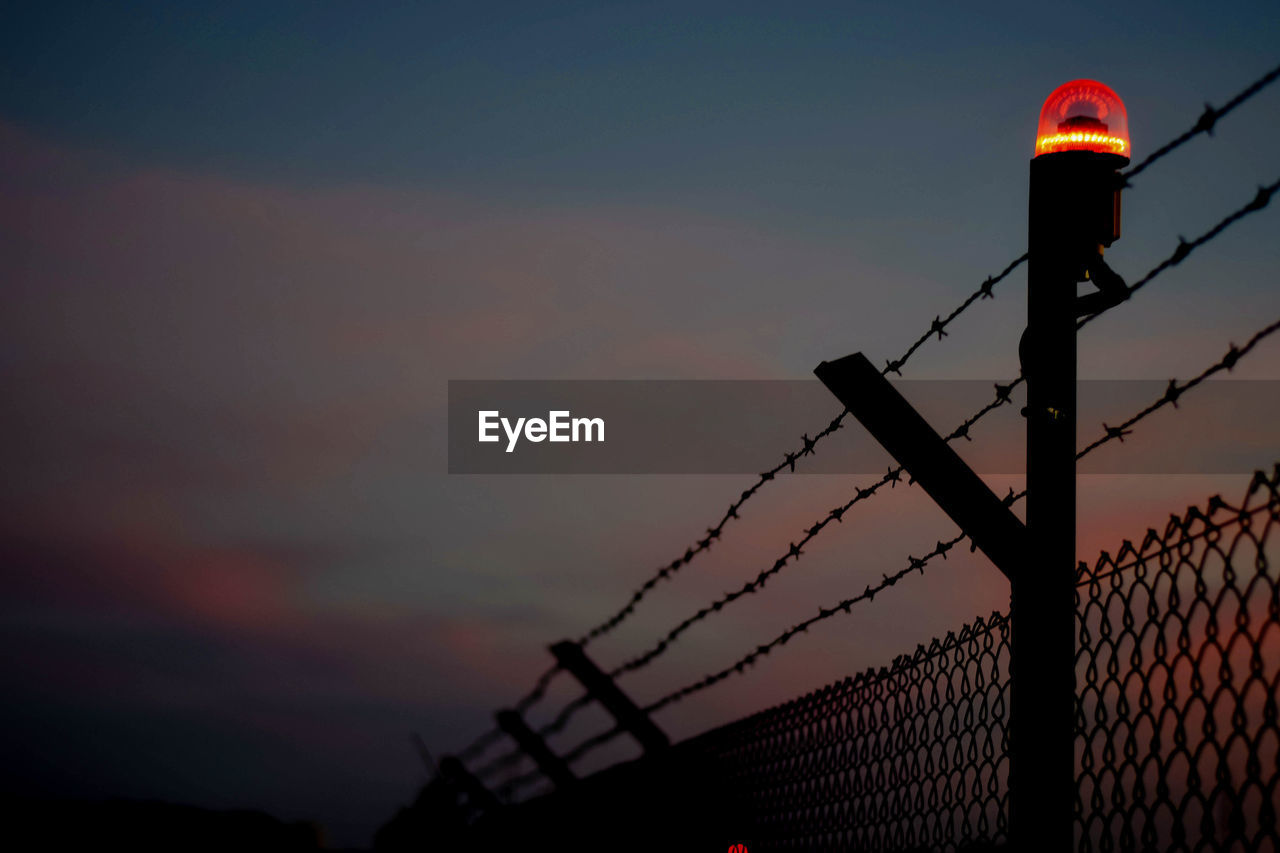 Low angle view of silhouette fence against sky during sunset