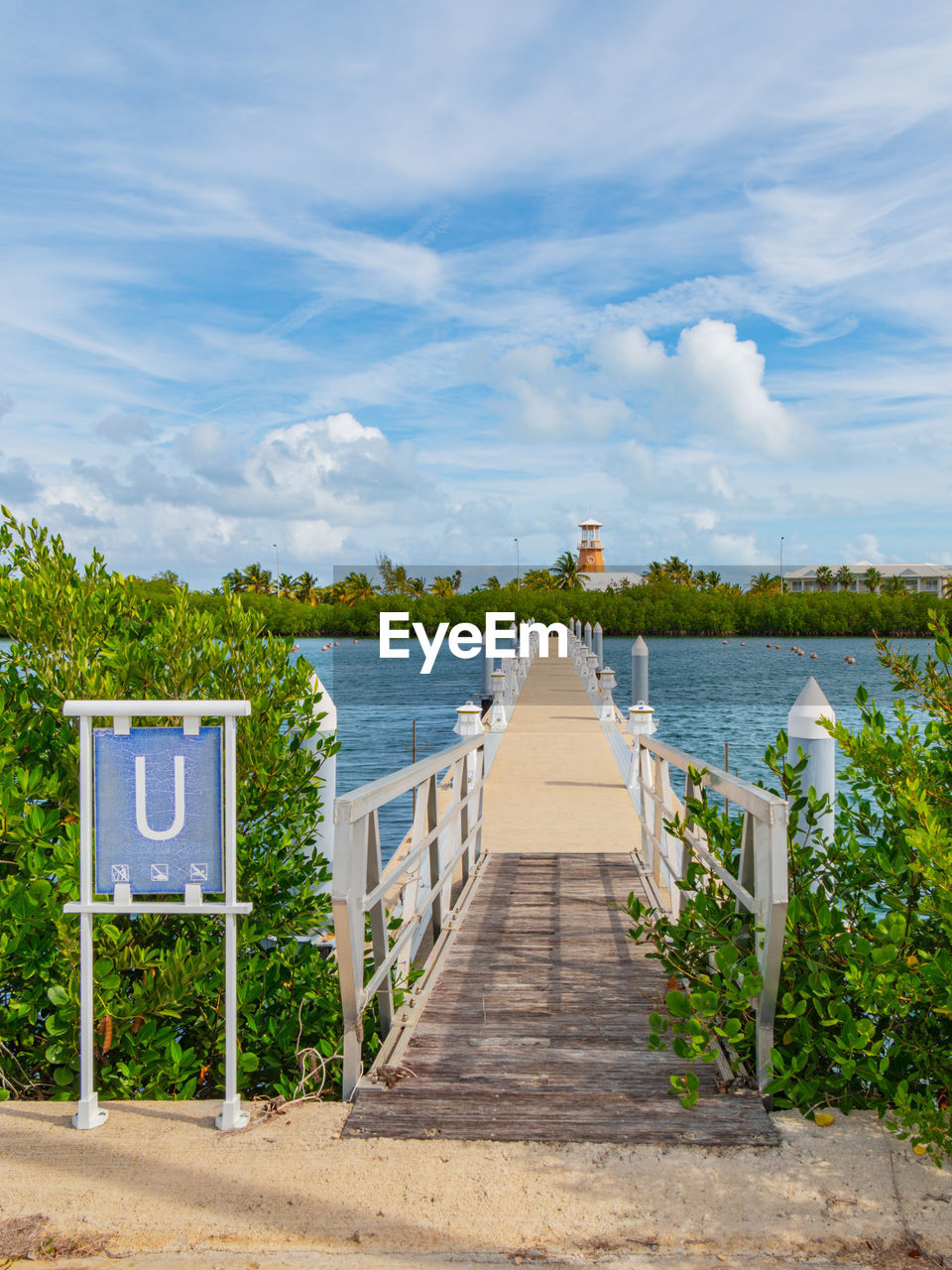 sky, water, cloud, nature, architecture, walkway, beach, sea, vacation, land, tranquility, plant, built structure, scenics - nature, travel destinations, no people, tree, footpath, the way forward, landscape, beauty in nature, travel, tranquil scene, environment, day, trip, outdoors, summer, blue, holiday, communication, tourism, wood, sign, road, sunlight, horizon, pier, city, transportation, idyllic, coast