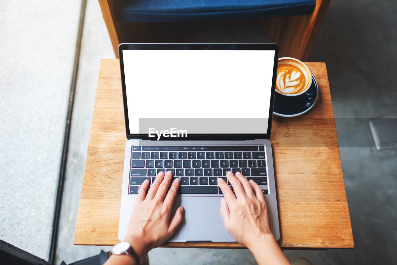 cropped hands using laptop at table