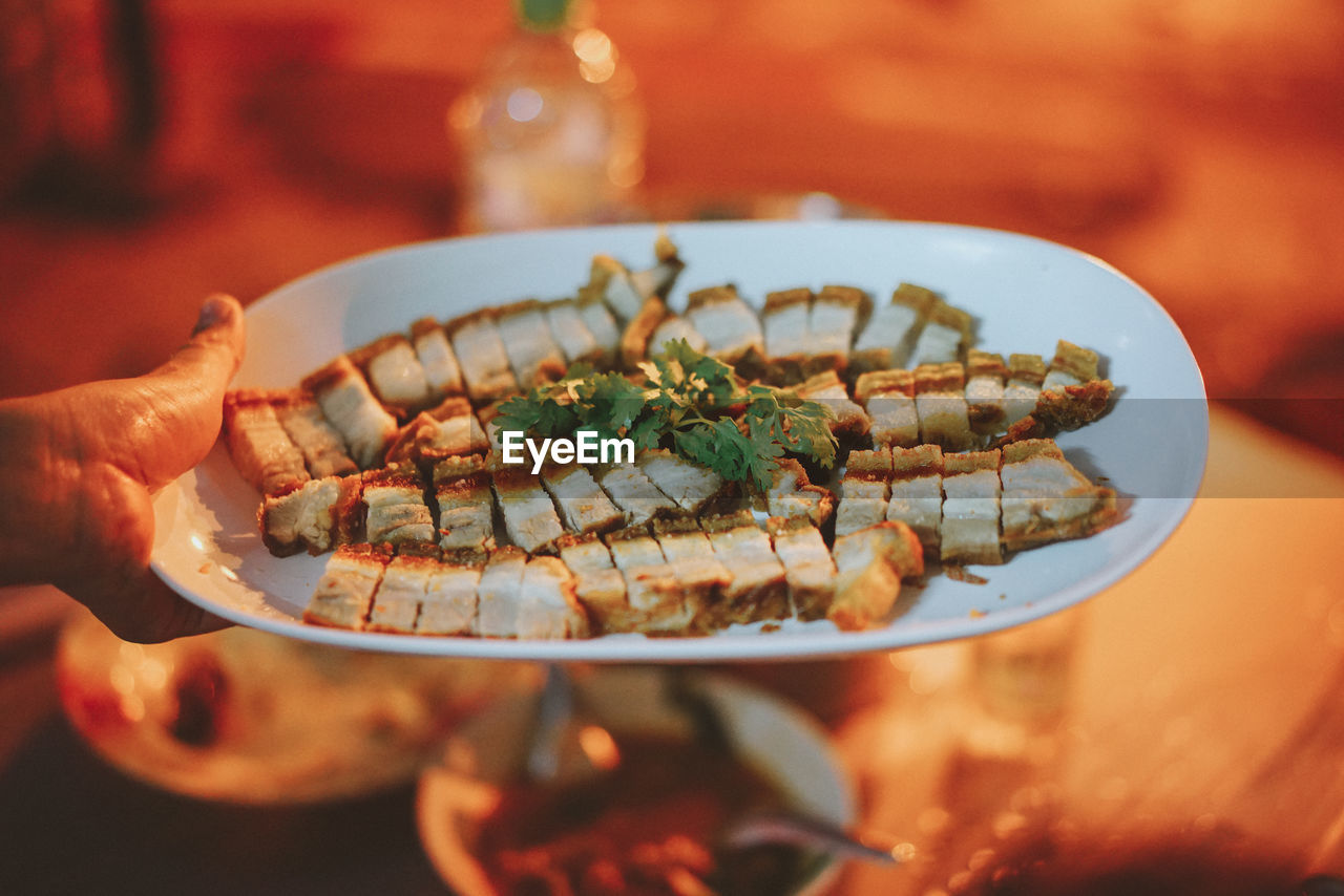 Close-up of hand holding bread in plate on table