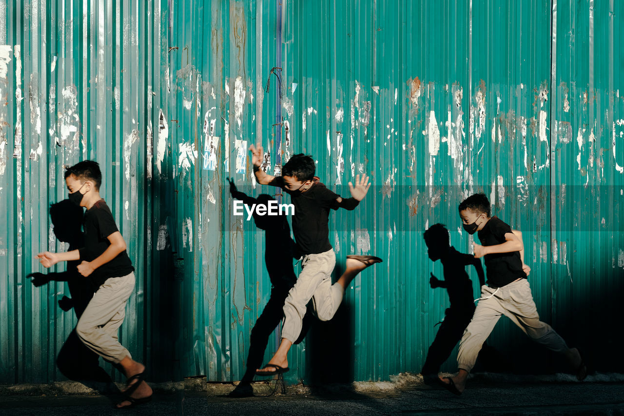 Boys running against corrugated wall