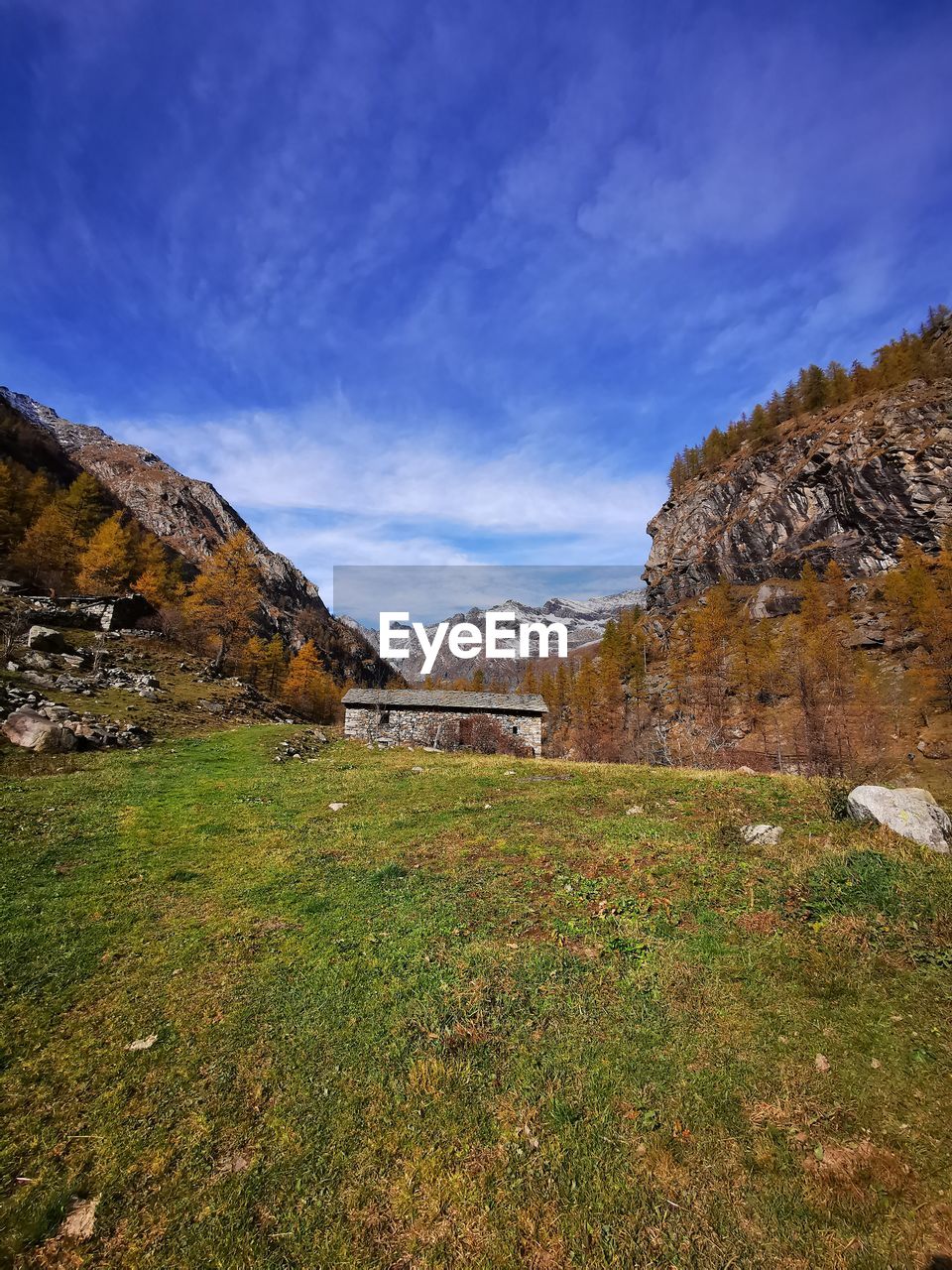sky, landscape, environment, nature, mountain, scenics - nature, land, plant, beauty in nature, grass, rock, wilderness, autumn, no people, travel destinations, travel, cloud, mountain range, architecture, valley, tranquility, non-urban scene, plateau, outdoors, tranquil scene, rural area, tourism, tree, blue, terrain, rural scene, meadow, building, day, field, built structure, water, highland