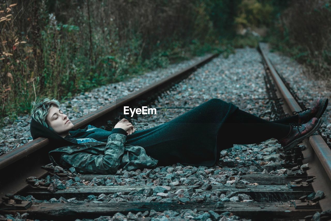 Young woman lying on railroad track