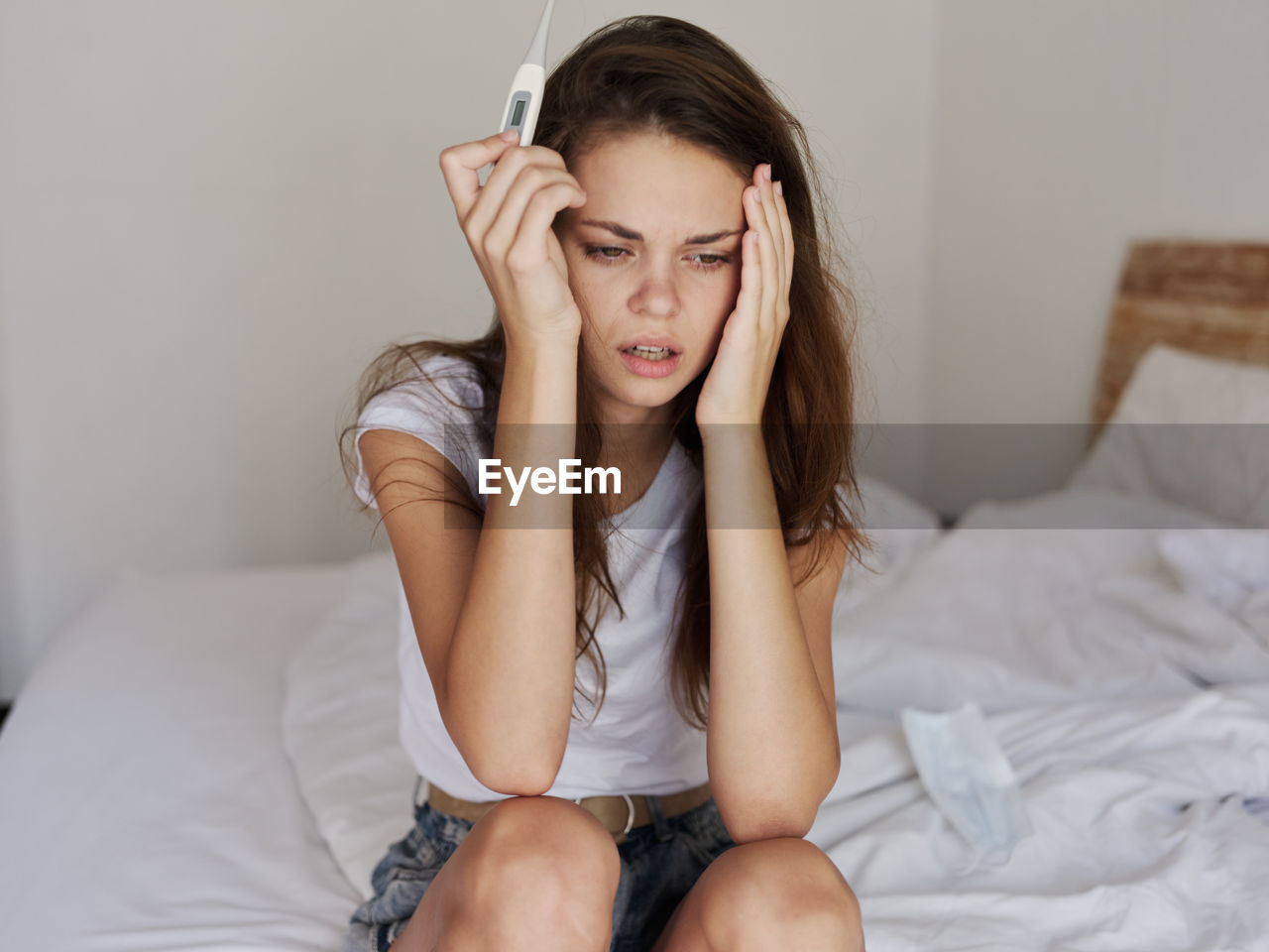 Young woman sitting on bed at home