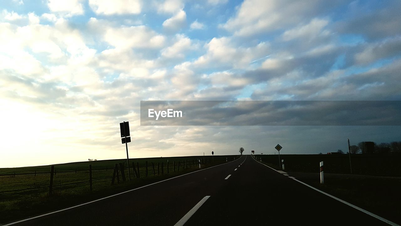 ROAD PASSING THROUGH ROAD AGAINST CLOUDY SKY