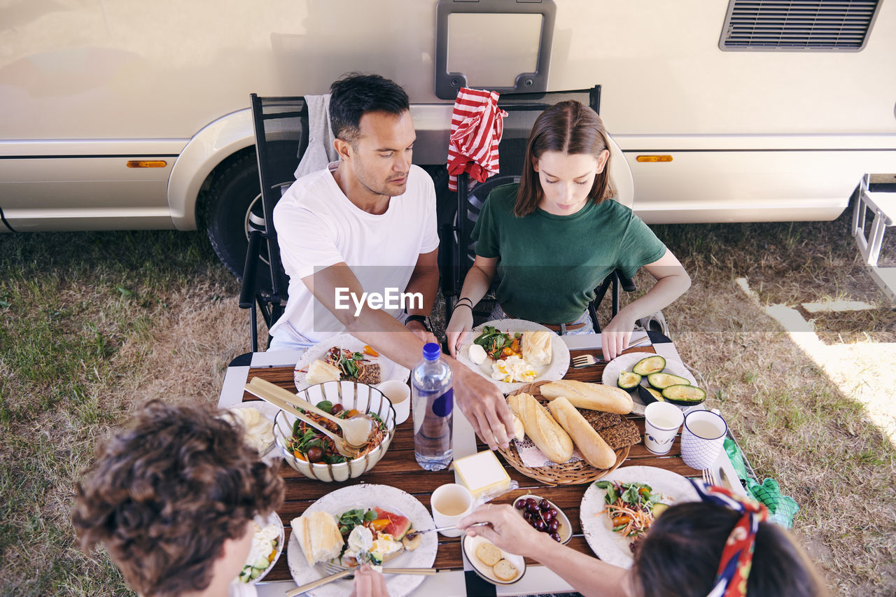 High angle view of parents and children having food at table in campsite