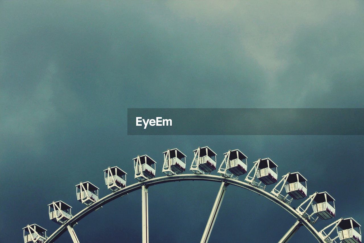 Low angle view of ferris wheel against cloudy sky at dusk