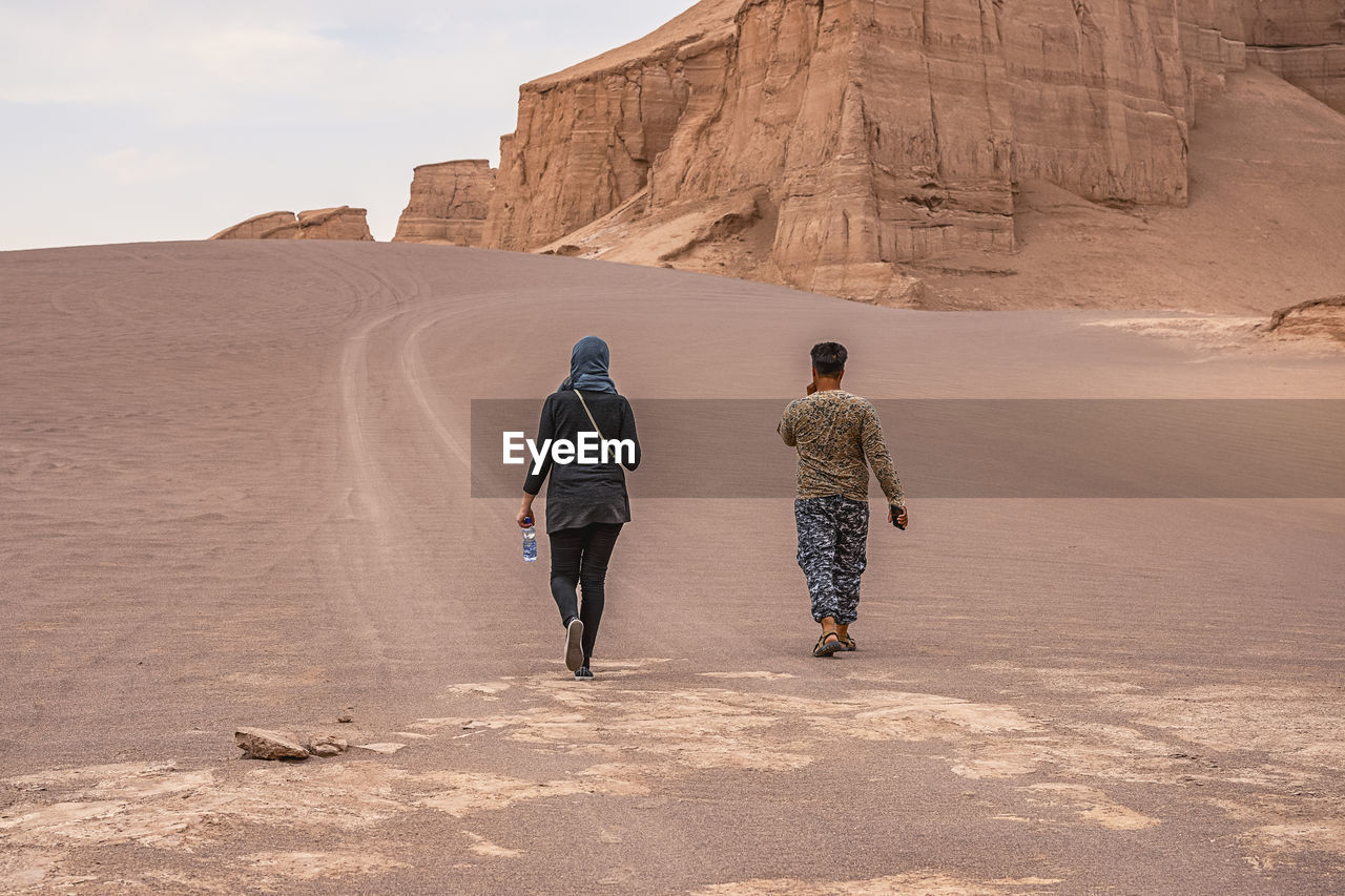 REAR VIEW OF WOMEN WALKING ON ROCK