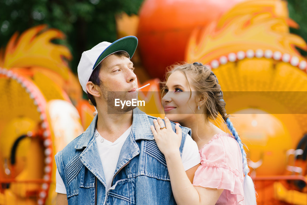 Happy couple in love having fun in an amusement park, eating lollipops person