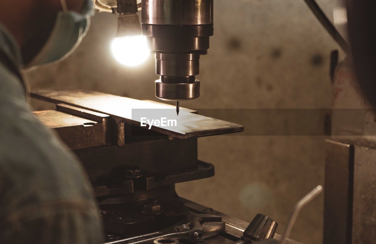 Milling machine working near worker with a protective mask. tool for cut metal workpiece. 