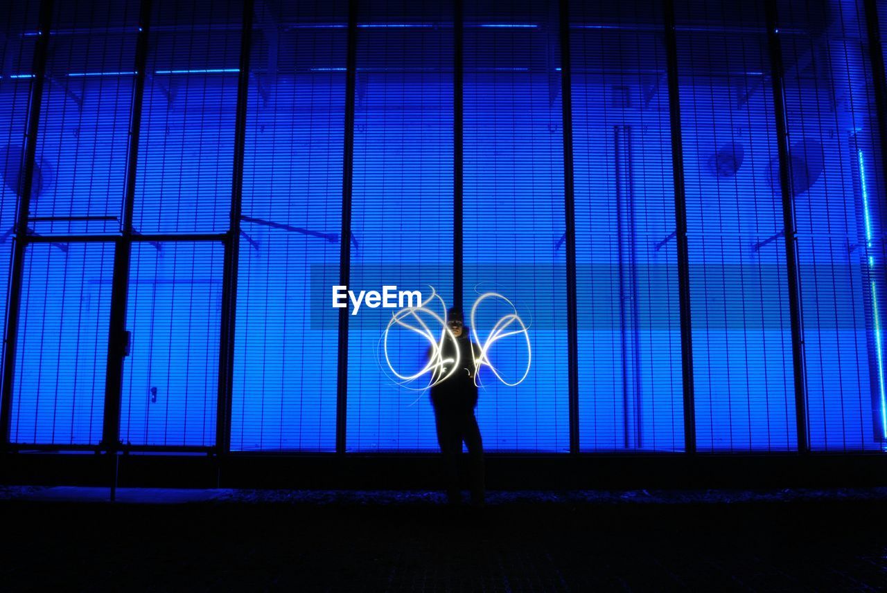 Man with light painting standing against blue wall