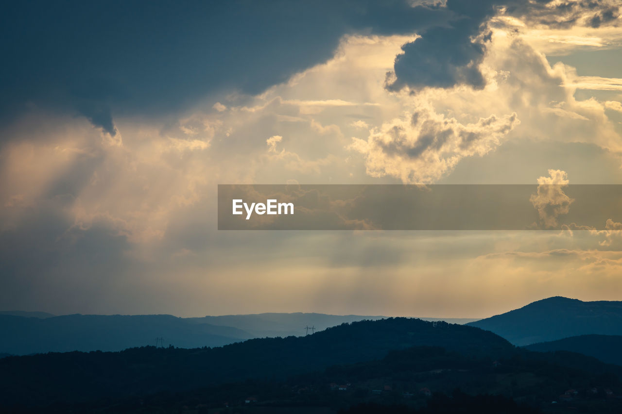 SCENIC VIEW OF DRAMATIC SKY OVER SILHOUETTE MOUNTAINS