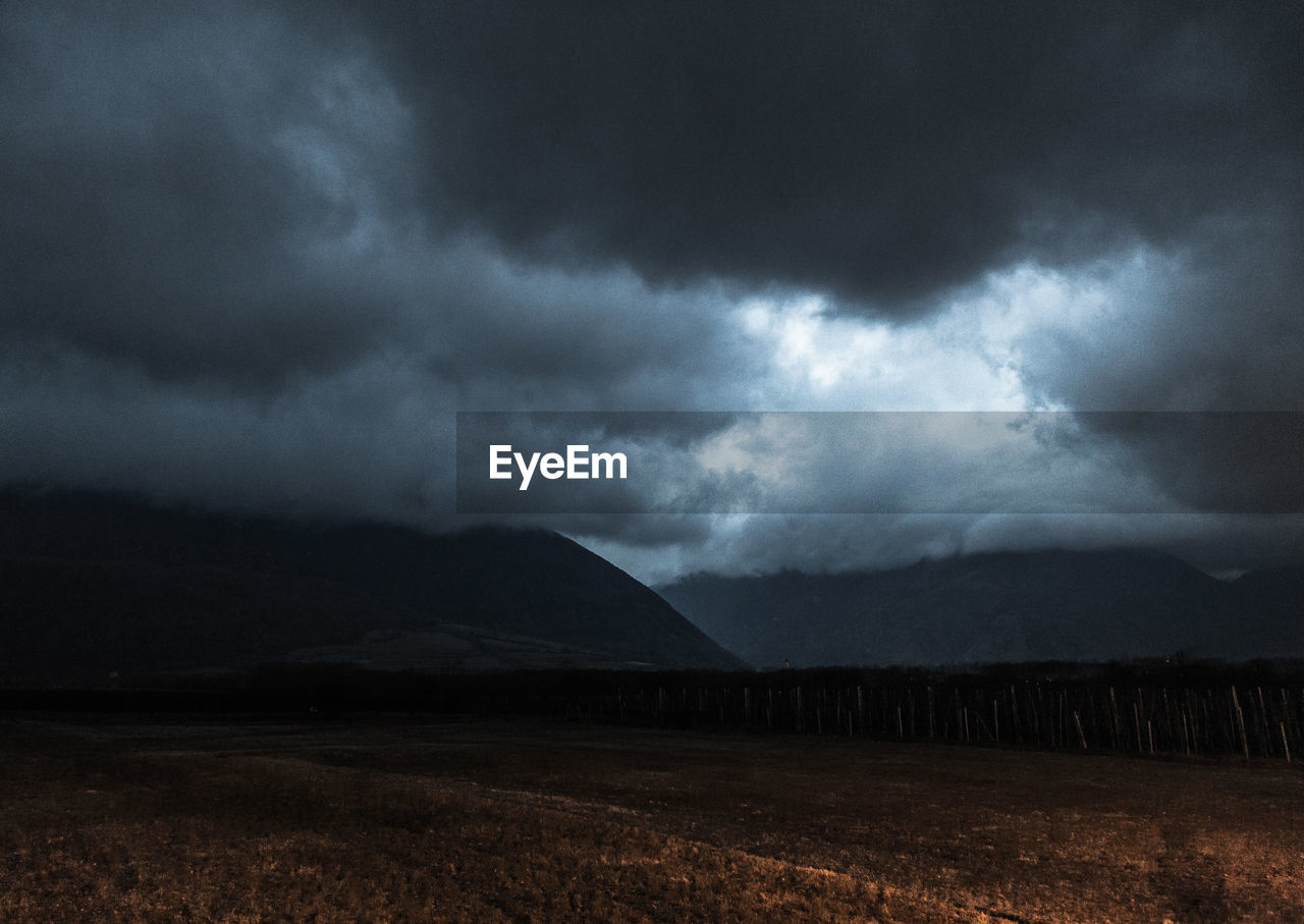 SCENIC VIEW OF STORM CLOUDS OVER FIELD