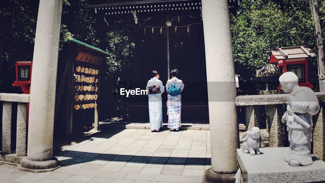 Rear view of woman wearing kimono walking towards shrine
