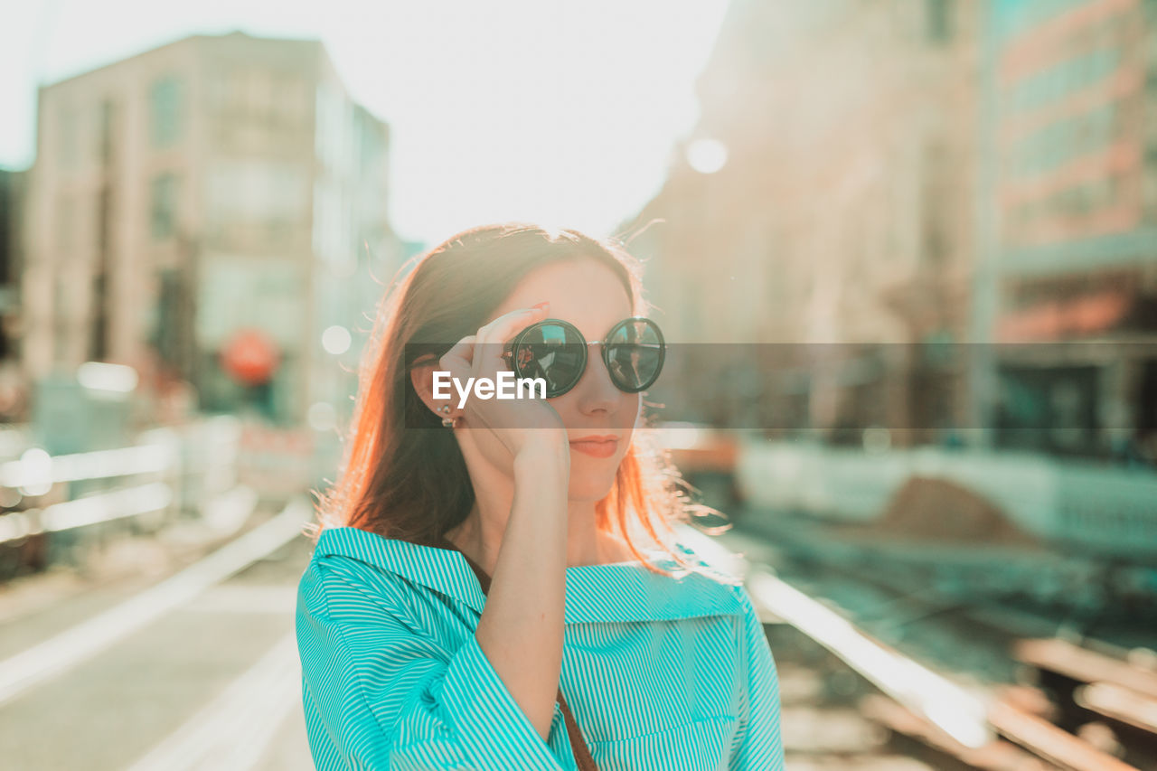 Young woman in sunglasses standing at city