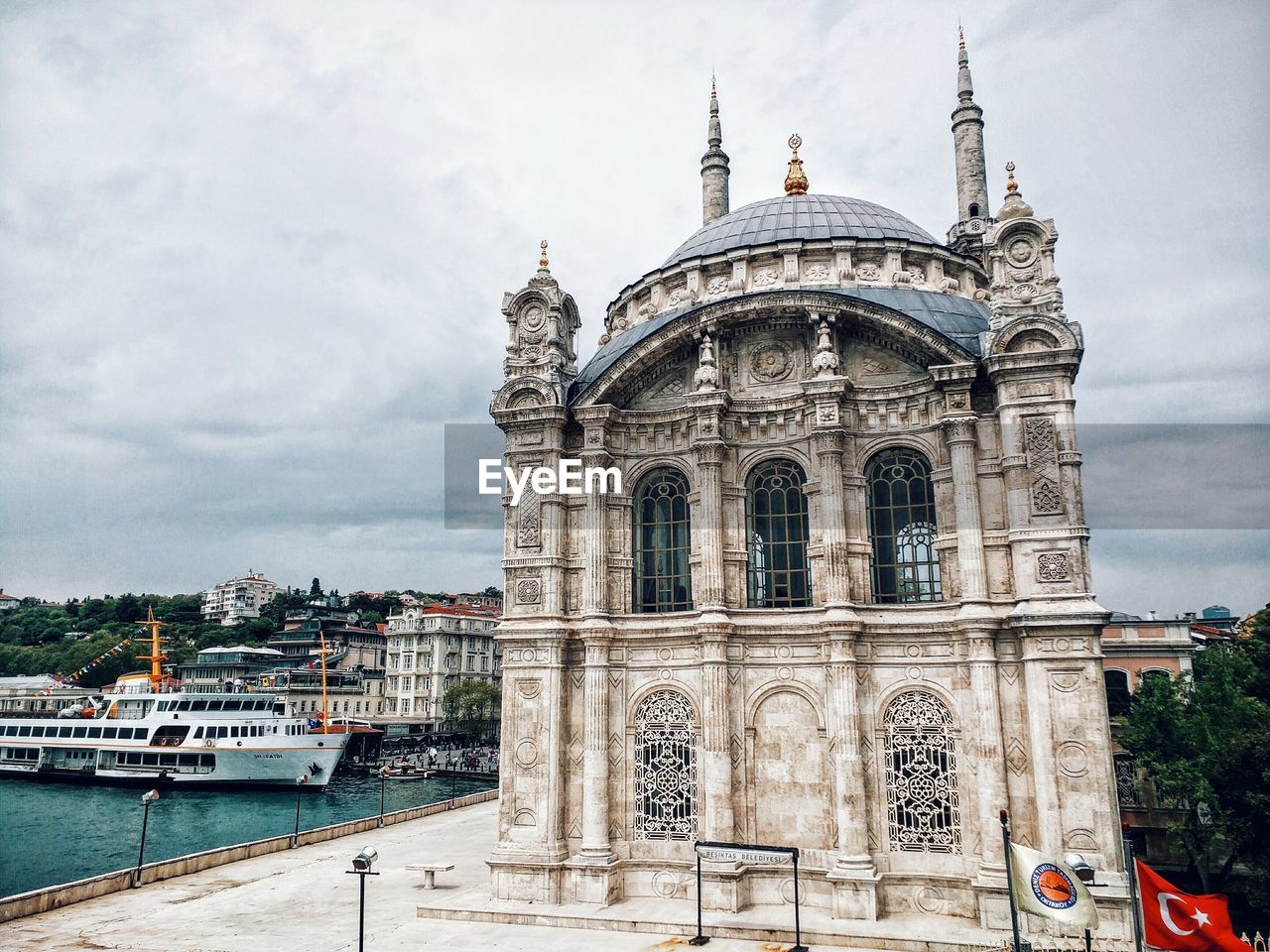 Exterior of ortakoy mosque by river against sky in city