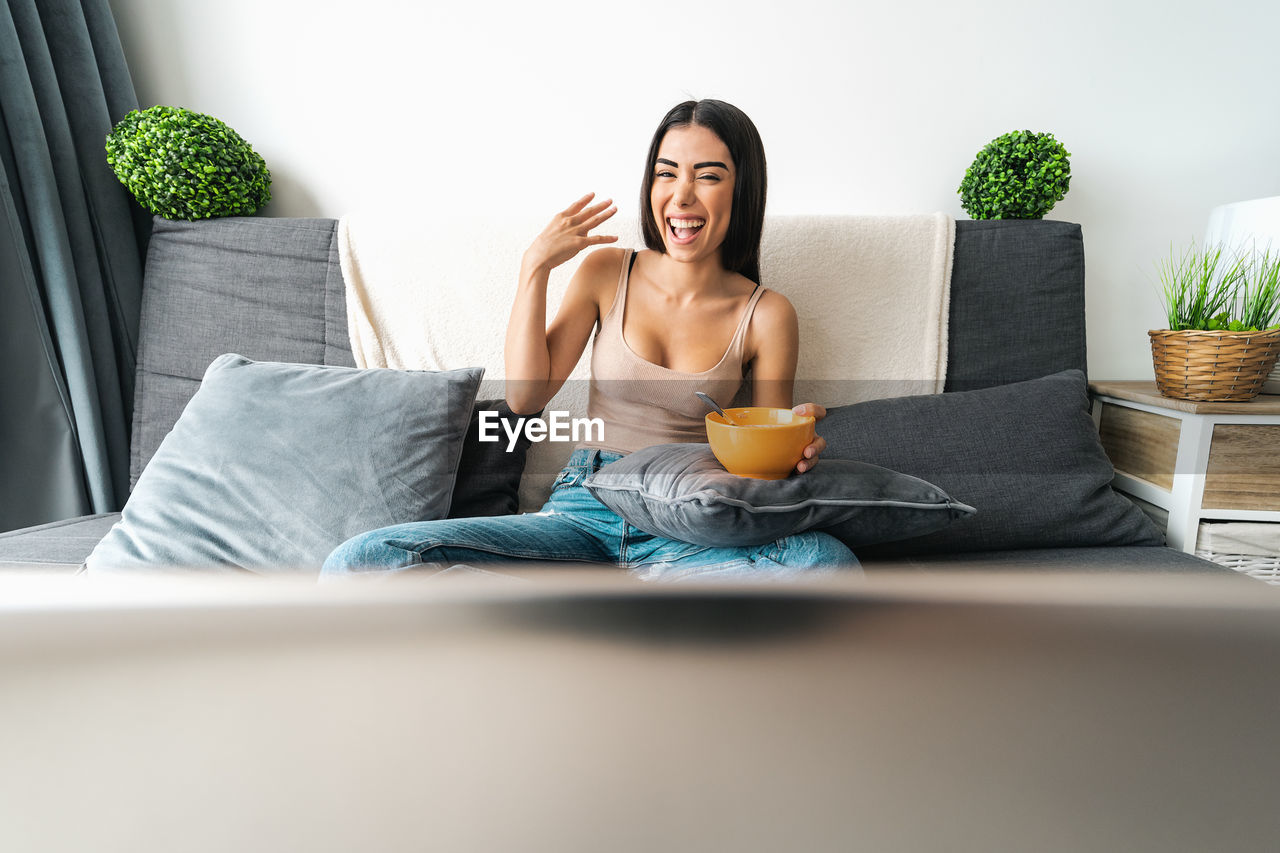 Cheerful woman watching tv at home