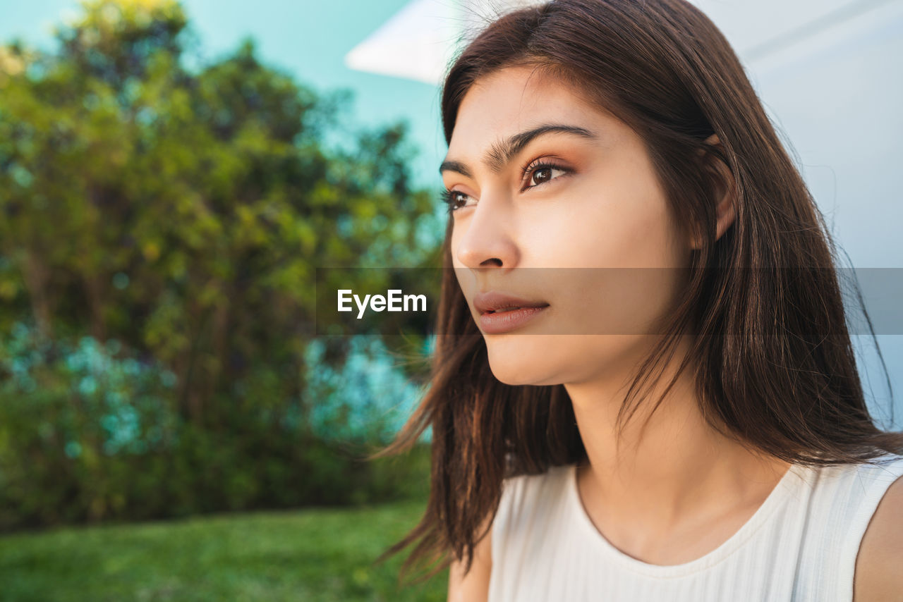Close-up of beautiful young woman looking away standing outdoors