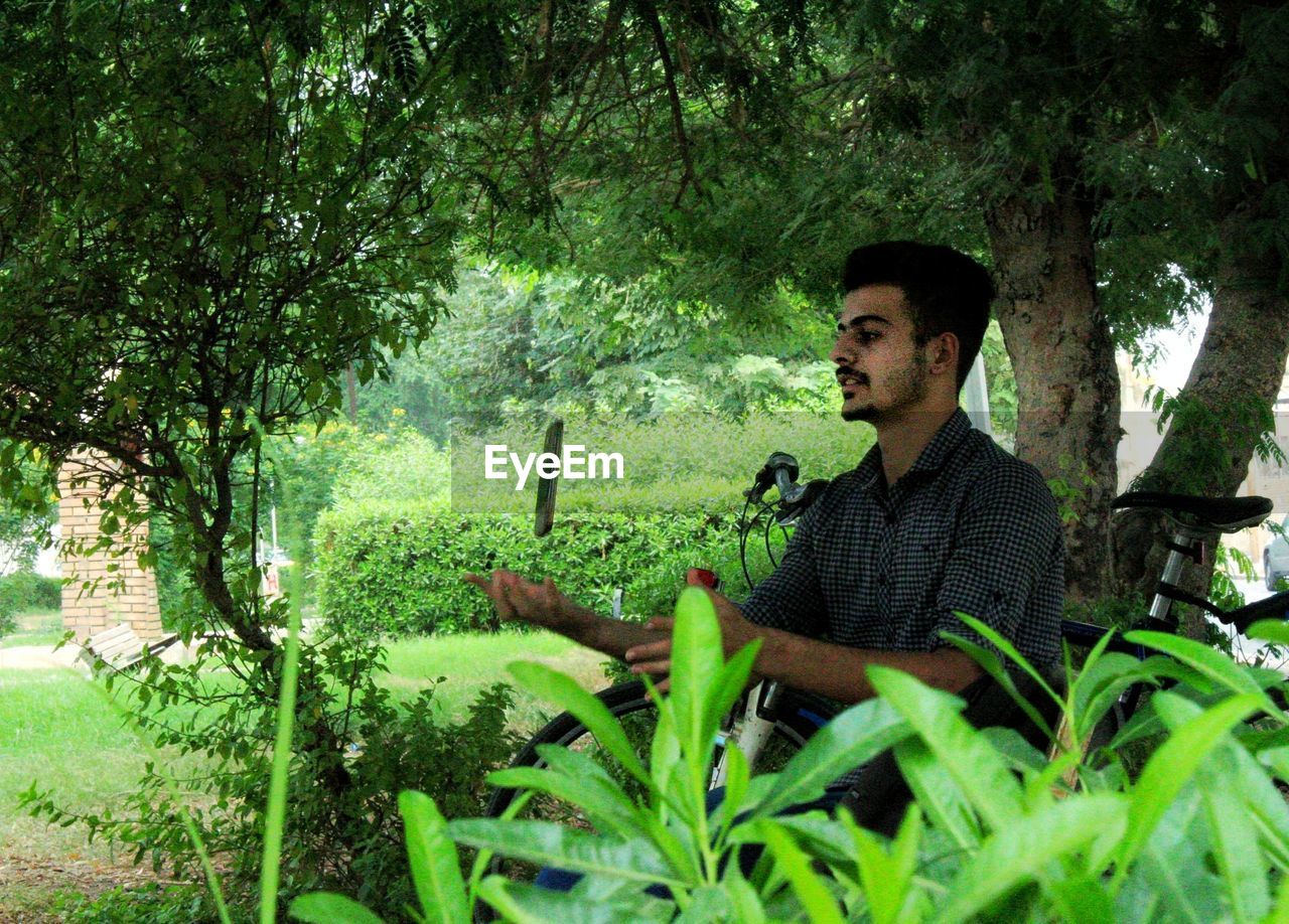 YOUNG MAN SITTING IN GARDEN