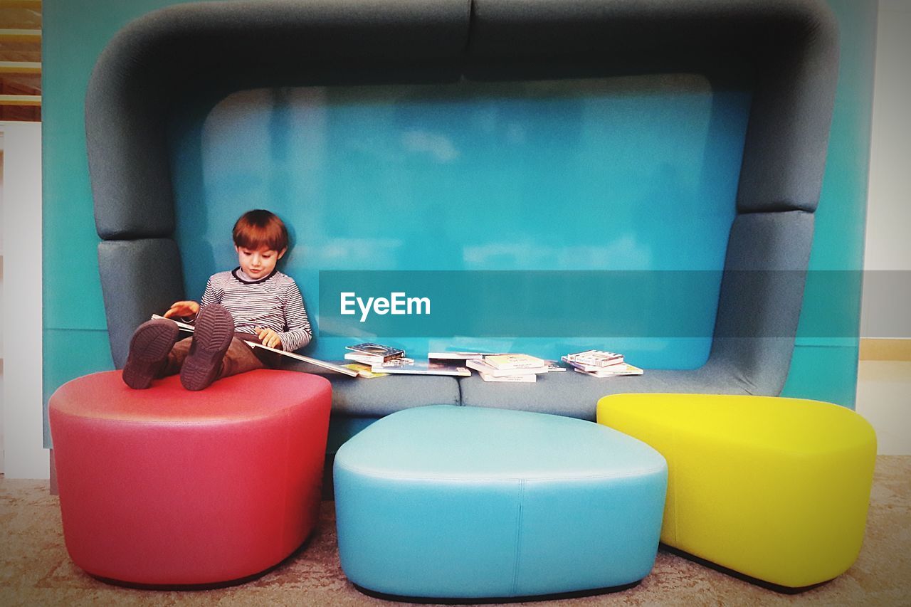 Boy reading book while sitting in furniture
