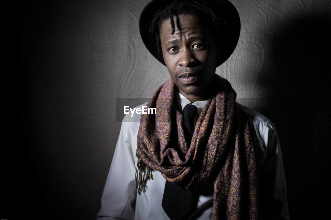 Portrait of man wearing scarf against wall