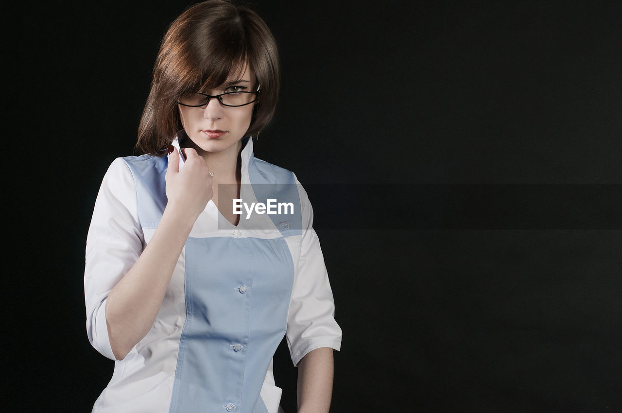 Portrait of beautiful woman standing against black background