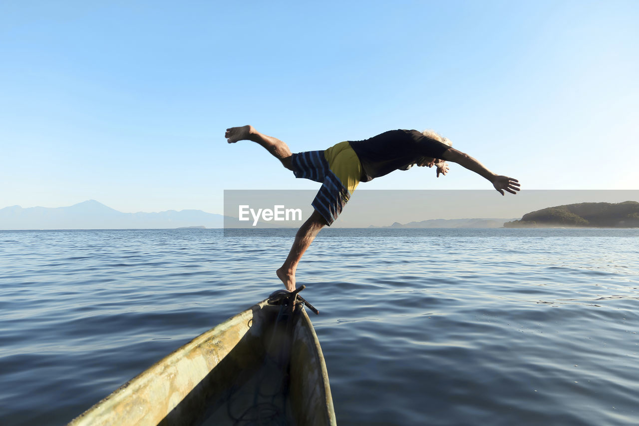 Man jumping from boat into sea