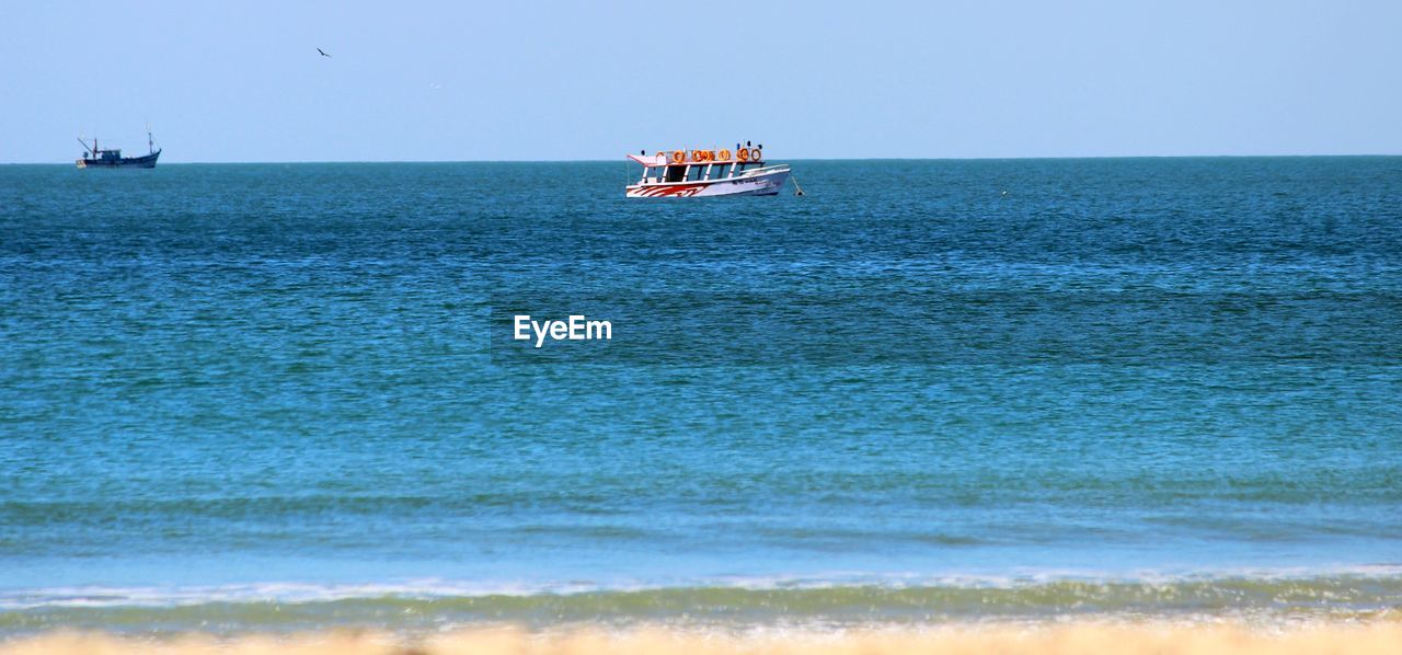 BOAT SAILING ON SEA AGAINST CLEAR SKY